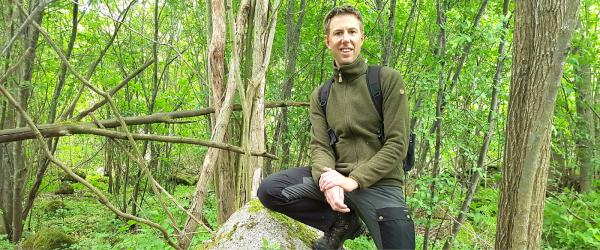 Bild av Daniel Ottosson som sitter på huk i skogen